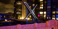 The X logo is illuminated atop its headquarters in San Francisco
